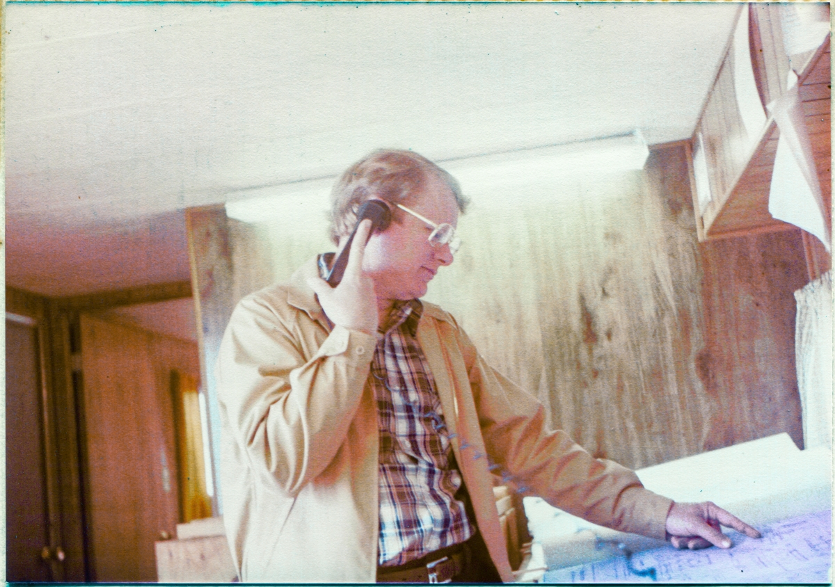 Image 011. Danny Sheffield in the Sheffield Steel field trailer at Space Shuttle Launch Complex 39-B, Kennedy Space Center, Florida. Danny was the son of Dan Sheffield, who owned Sheffield Steel, and he would occasionally pay the jobsite a visit, making sure that all was well, in addition to working liaison with Sheffield’s fabrication shop in Palatka, Florida, if necessary. Here we see Danny on the phone, finger to a blueprint, working some issue or other regarding the structural steel that Sheffield furnished and delivered as their part of the work effort during the construction of the Rotating Service Structure at Pad 39-B. Photo by James MacLaren. Image 011. Danny Sheffield in the Sheffield Steel field trailer at Space Shuttle Launch Complex 39-B, Kennedy Space Center, Florida. Danny was the son of Dan Sheffield, who owned Sheffield Steel, and he would occasionally pay the jobsite a visit, making sure that all was well, in addition to working liaison with Sheffield’s fabrication shop in Palatka, Florida, if necessary. Here we see Danny on the phone, finger to a blueprint, working some issue or other regarding the structural steel that Sheffield furnished and delivered as their part of the work effort during the construction of the Rotating Service Structure at Pad 39-B. Photo by James MacLaren.